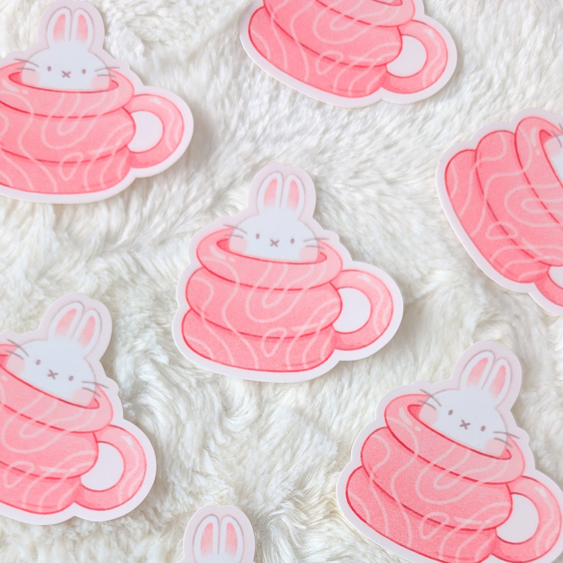 Stickers of bunnies in hot chocolate cups on a textured white background
