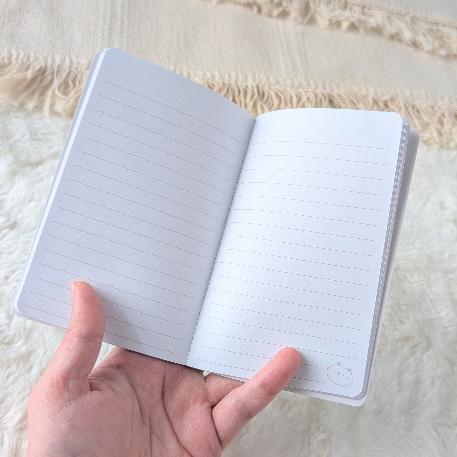 Hand holding an open notebook with lined pages on a textured fabric background