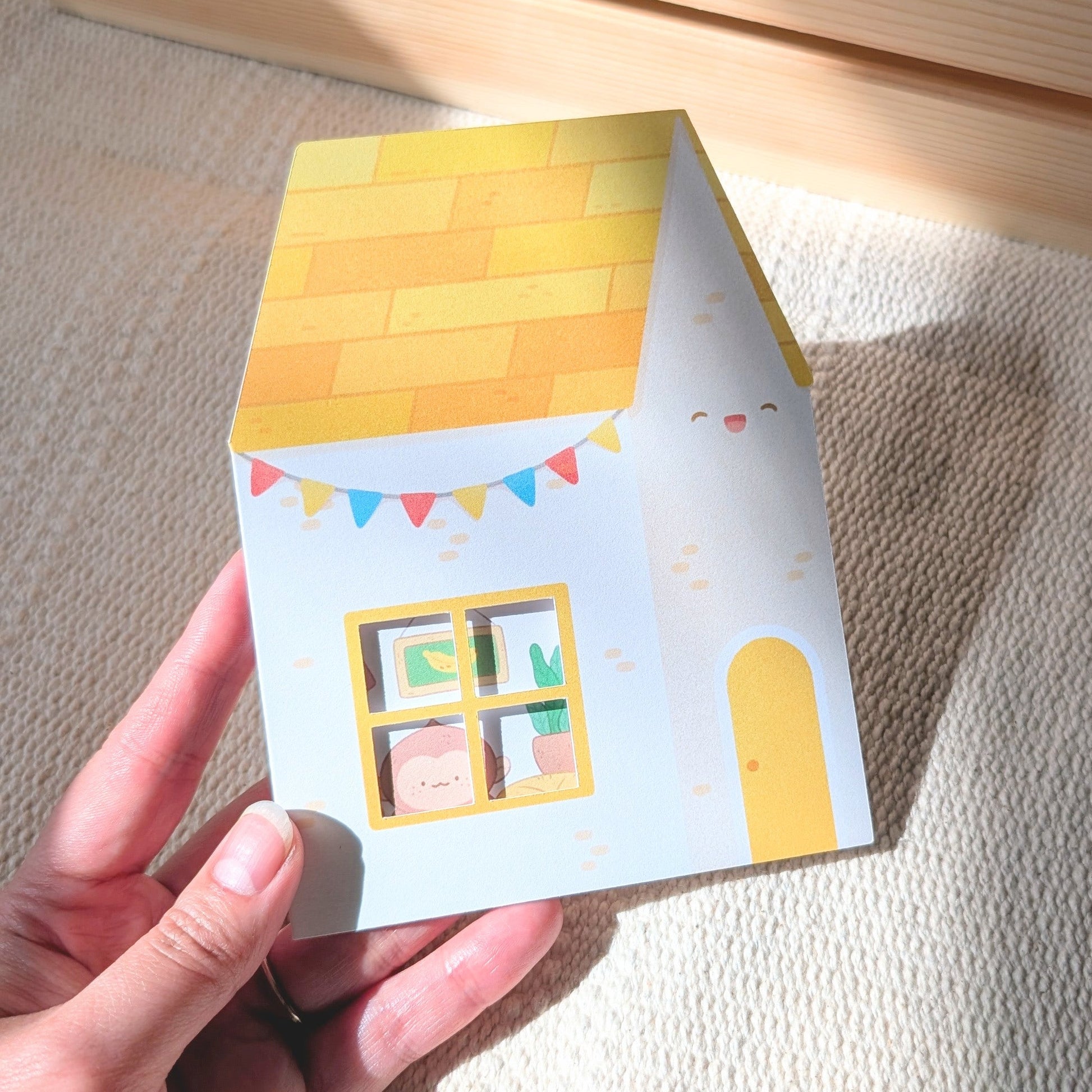 Hand holding a small card with a house design on a textured surface