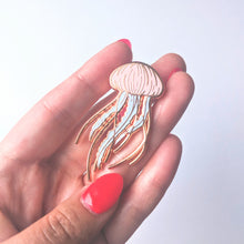 Load image into Gallery viewer, A close up of a rose gold jellyfish enamel pin being held by a hand with red nails
